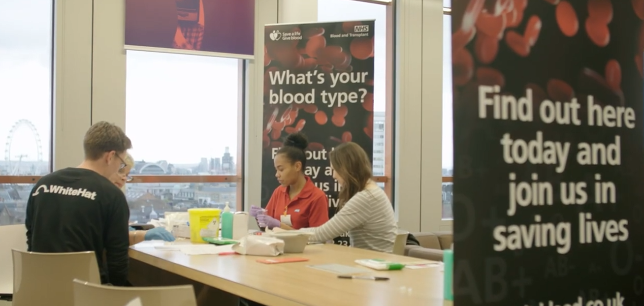 A screenshot from the YouTube video of four people at a 'What's Your Blood Type' event